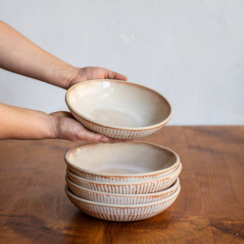 A stack of Workshop Stu bowls, hands holding the top bowl, presenting the interior to the viewer.
