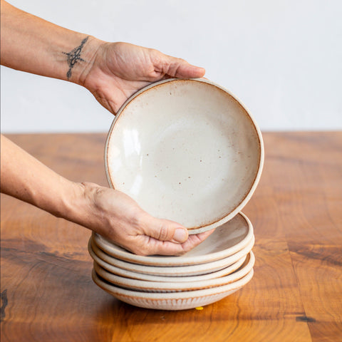 Hands picking up a Dessert Bowl from a Stack of Bowls