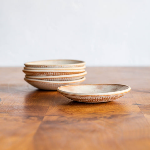 A Stack of Dessert Bowls next to a single bowl, showcasing the subtle textures of the Workshop Collection