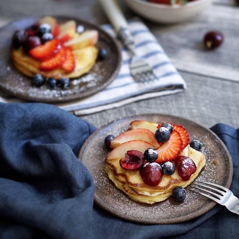 Progress Cafe Plate glazed in Brown Leather Matte, with berries and crepes. Displayed on dining napkins with forks