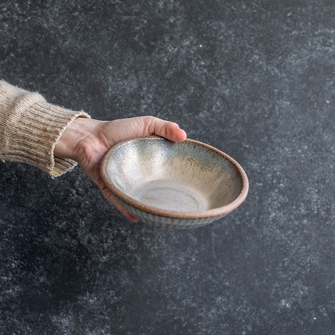Hand displaying a Progress Small Soup Bowl glazed in Moonshadow.