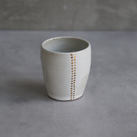 White ceramic cup with gold accents on a gray background