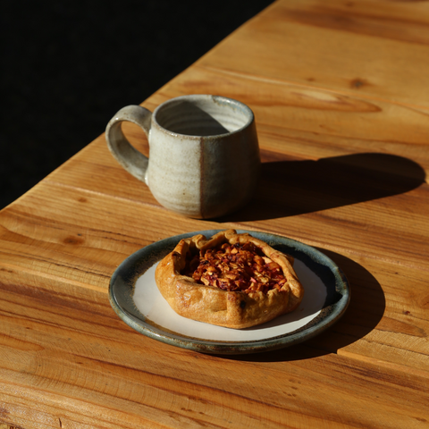 Short Tulip Cup and Inkblot Side Plate with Fruit Galette on a wooden table in the sun with dramatic shadows