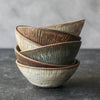 Progress Cereal Bowls stacked, displaying tick mark etched textures on the exterior, in a variety of glazes