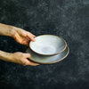 Hands holding Progress Soups Bowl and Pasta Bowl glazed in White Chamois