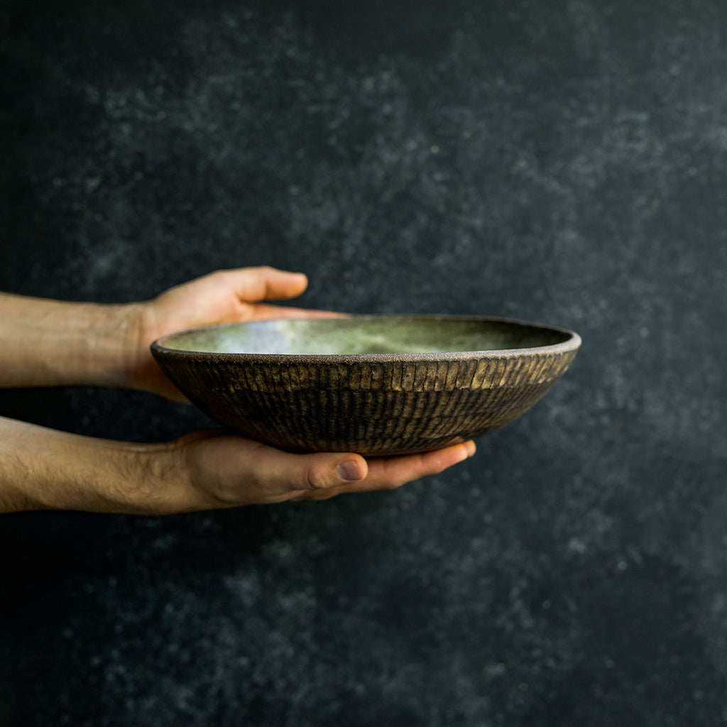 Hand displaying a Progress Fruit Bowl glazed in Moss Green